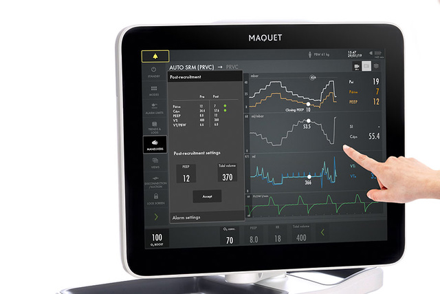 Person interacting with a medical monitoring screen displaying various health data and graphs.
