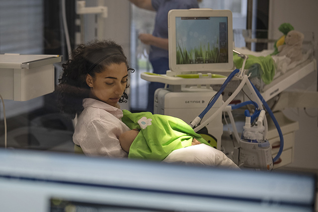 Mother holding premature baby requiring mechanical ventilation from Servo-n in NICU ward 