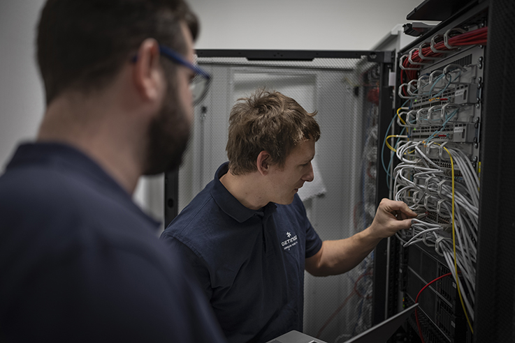 Engineers installing Servo TwinView software in hospital IT server room cabinet