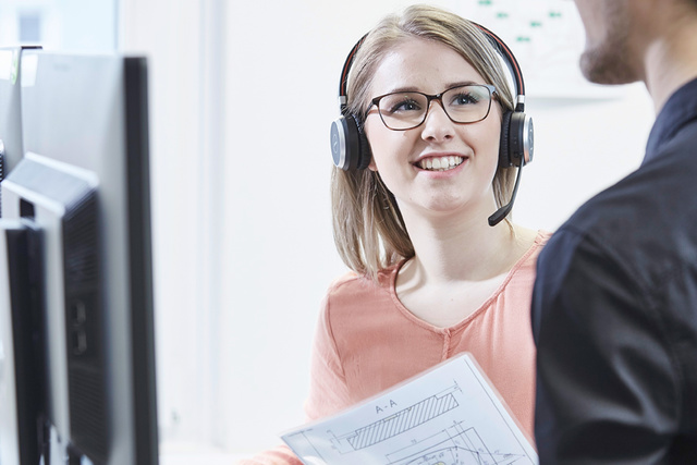 Auszubildende mit Headset im Gespräch mit einem Kollegen