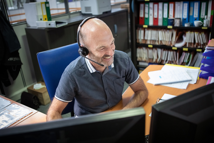 Man with headphones at the desk smiling