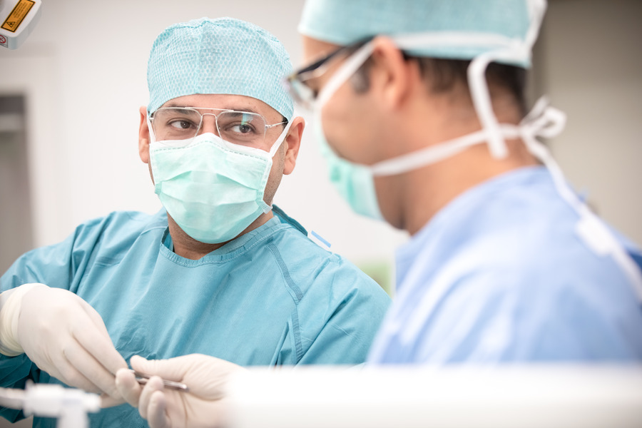 Surgeons looking at each other and handing over an item Surgeons looking at each other and handing over an item