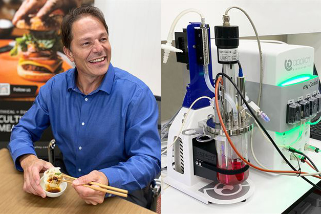 A person in a blue shirt uses chopsticks beside a laboratory device with tubes and a digital display.
