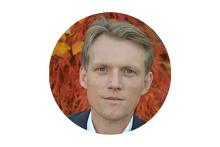 Person med kort hår mot levande orange och gul lövverk bakgrund.
