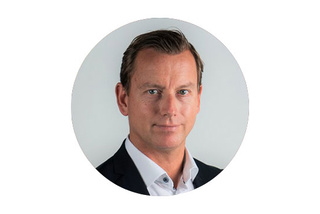 Man i kostym och vit skjorta mot en vit bakgrund, ser fram emot.