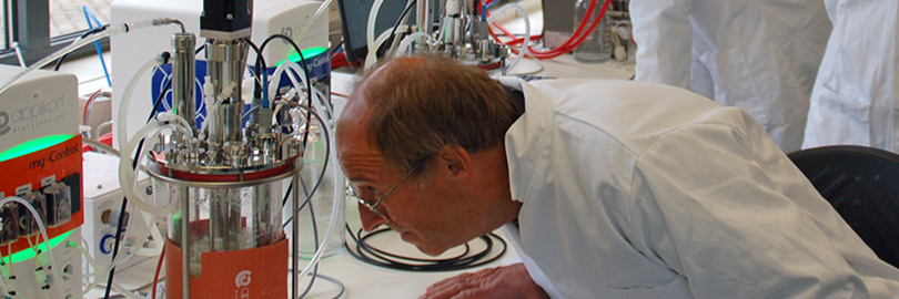 Ein Wissenschaftler untersucht Geräte in einem Labor, umgeben von verschiedenen Geräten und Kabeln.