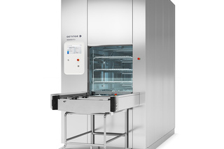 Large industrial sterilizer with an open chamber and control panel, designed for medical equipment cleaning.