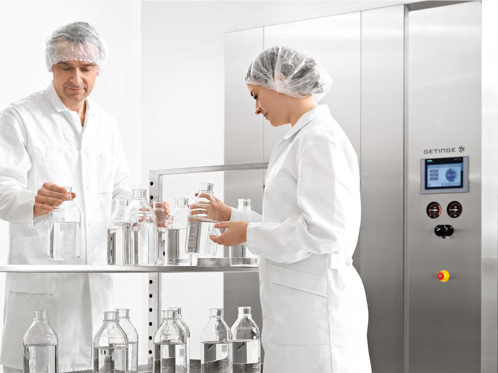 GSS R Steam Sterilizer for lab and biomedical research with a man and a woman working in front with the loading equipment