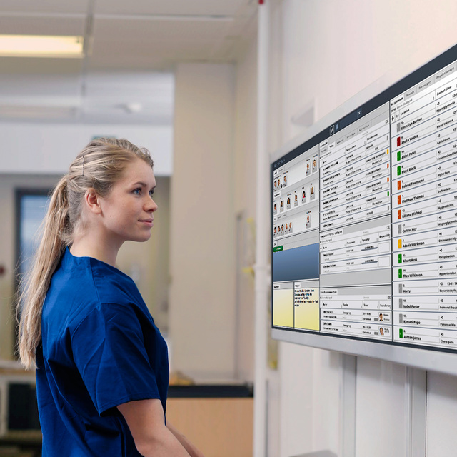 Nurse in front of a big INSIGHT screeen looking at the patient list with the next medical activities