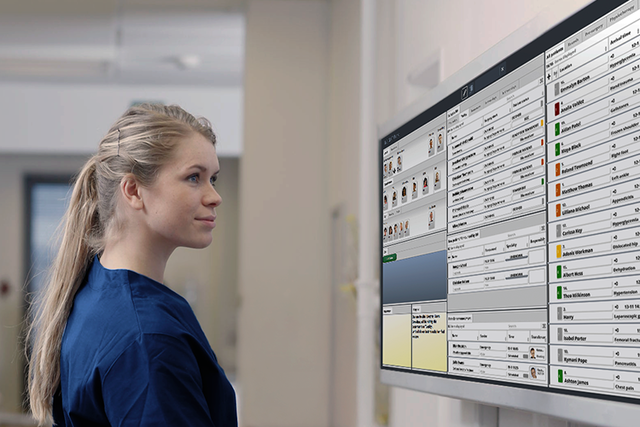 Nurse in front of a big monitor watching at the INSIGHT screen, showing patient list and available staff