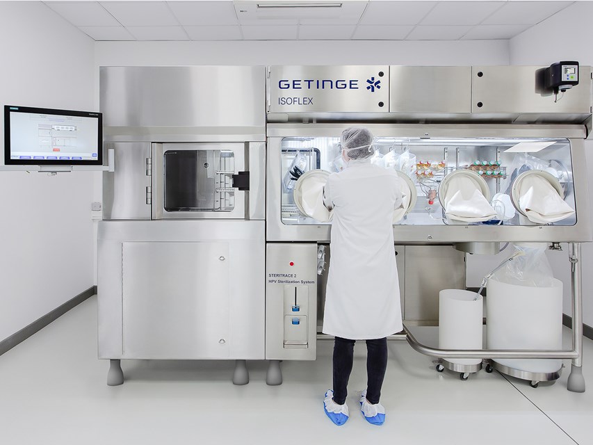 Operator performing sterility testing in a 4-glove ETF ISOFLEX isolator.