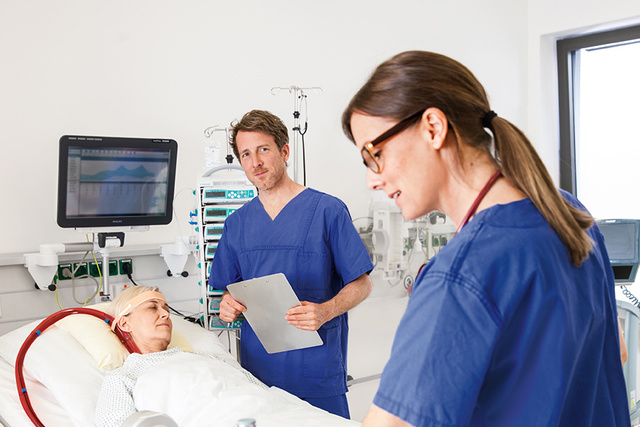 Close up of clinician in front of ECMO patient in ICU bed
