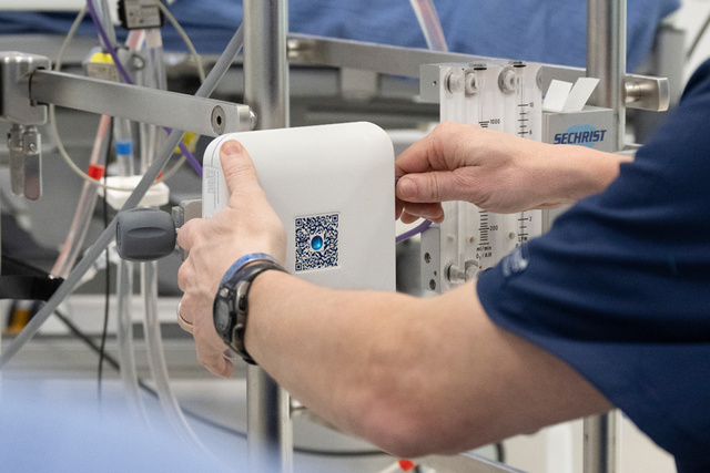 A medical professional adjusts equipment on a stainless steel medical cart, focusing on a Talis Hub device