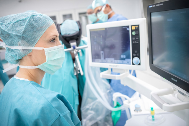 A woman in medical scrubs observes a monitor, engaged in her work related to healthcare or patient care.