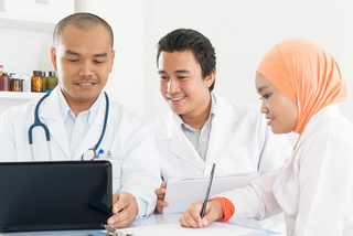 Three doctors looking at computer for a webinar