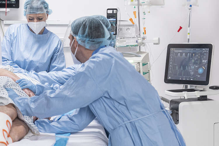 Getinge Servo-u mechanical ventilator in clinical environment showing patient being rolled into prone position by clinicians Getinge Servo-u mechanical ventilator in clinical environment showing patient being rolled into prone position by clinicians