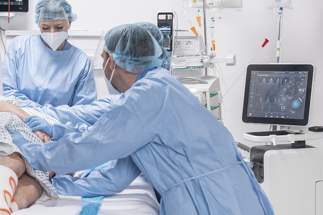 Getinge Servo-u mechanical ventilator in clinical environment showing patient being rolled into prone position by clinicians 