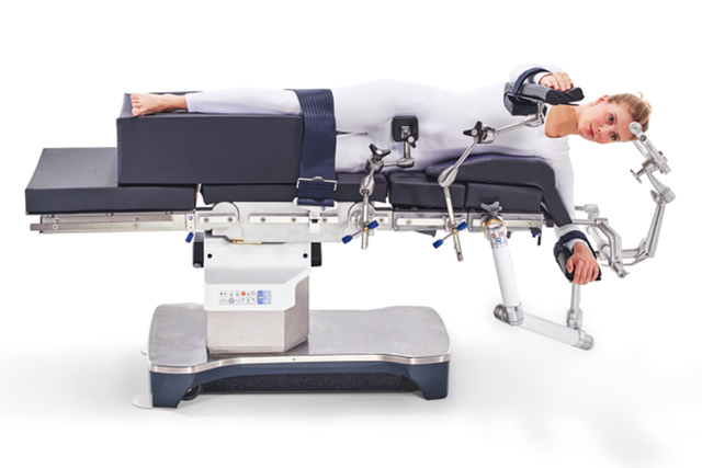 Person in white suit positioned on a surgical table with support straps, demonstrating its functionality.
